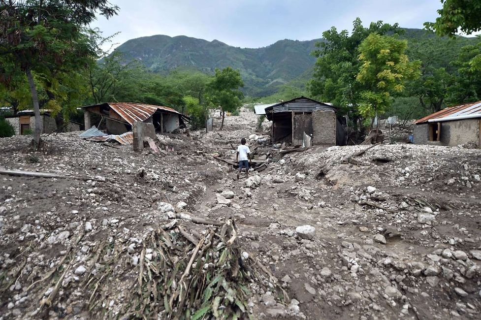 August 29, 2015, a boy walking past houses destroyed by a mudslide caused by the rains from Tropical Storm Erika in Montrouis, Haiti. 