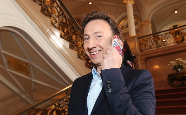 Dans les escaliers du palais grand-ducal, Stéphane Bern affiche un drapeau luxembourgeois sur son smartphone