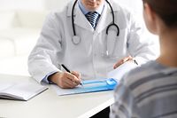 Doctor consulting patient at desk in clinic, closeup
