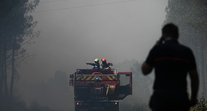 TOPSHOT - Firefighters stand guard to monitor fire outbreaks and restarts near Saint-Magne, southwestern France on August 10, 2022. (Photo by Philippe LOPEZ / AFP)