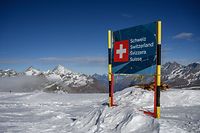 A photograph taken on November 28, 2020 shows a banner marking the Swiss border near the 3,480-metre high Rifugio Guide del Cervino refuge at Testa Grigia peak between Zermatt Switzerland and Breuil-Cervinia, Italy. - Way up in the snowy Alps, the border between Switzerland and Italy has shifted due to a melting glacier, putting the location of an Italian mountain refuge in dispute. The border line runs along the drainage divide -- the point at which meltwater will run off down either side of the mountain towards one country or the other. But the Theodul Glacier's retreat means the watershed has crept towards the Rifugio Guide del Cervino, by the 3,480-metre high Testa Grigia peak -- and is gradually sweeping underneath the building. (Photo by Fabrice COFFRINI / AFP)