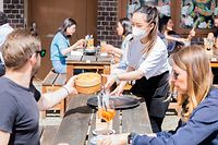 24.05.2021, Berlin: Thuy Nhi Nguyen (M), Kellnerin, bedient im Berliner Bezirk Prenzlauer Berg in einem Restaurant für asiatische Fusionsküche Gäste. Foto: Christoph Soeder/dpa +++ dpa-Bildfunk +++