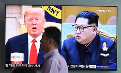 A man walks past a television news screen showing US President Donald Trump (L) and North Korean leader Kim Jong Un (R), at a train station in Seoul on June 11, 2018.
Kim Jong Un and Donald Trump will meet on June 12 for an unprecedented summit in an attempt to address the last festering legacy of the Cold War, with the US President calling it a "one time shot" at peace. / AFP PHOTO / Jung Yeon-je
