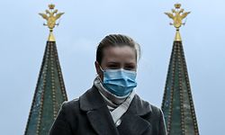 A woman wearing a face mask to protect against the coronavirus disease walks in front of two-headed eagles, the national symbol of Russia, at the top a building on Red Square in downtown Moscow on October 19, 2020, amid the COVID-19 coronavirus pandemic. - Russia confirmed 15,982 new Covid-19 cases on October 19, 2020. (Photo by Kirill KUDRYAVTSEV / AFP)