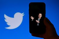 (FILES) In this file illustration photo taken on October 4, 2022, a phone screen displays a photo of Elon Musk with the Twitter logo shown in the background in Washington, DC. - The New York Stock Exchange did not permit trading on Twitter on October 28, 2022 after Elon Musk completed a $44 billion takeover of the social media platform. Twitter was listed among the companies experiencing a "trading halt," according to an NYSE notice that said the merger was "effective." (Photo by OLIVIER DOULIERY / AFP)