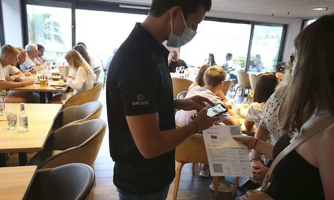 A waiter checks a diner's health pass