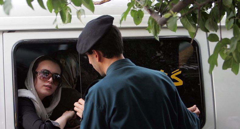 (FILES) In this file photo taken on July 23, 2007, an Iranian policeman speaks with a woman siting in a police car after she was arrested because of her "inappropriate" clothes during a crackdown to enforce Islamic dress code in the capital Tehran. - Iran has scrapped its morality police after more than two months of protests triggered by the arrest of Mahsa Amini for allegedly violating the country's strict female dress code, local media said on December 4, 2022. (Photo by Behrouz MEHRI / AFP)