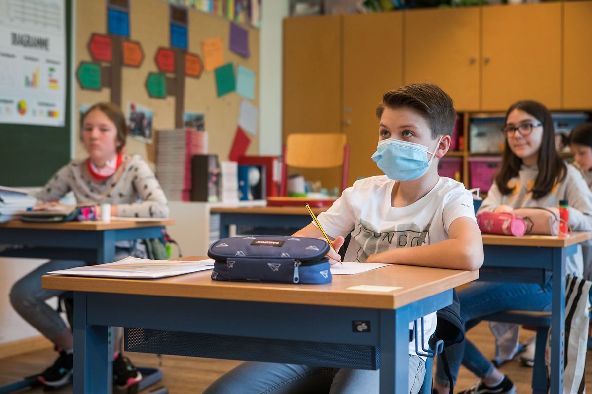 Die Schüler sitzen an einzelnen Bänken. Manche haben ihre Maske während dem Unterricht anbehalten. 
