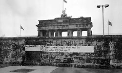 06.10.1988, Berlin: Eine Frau betrachtet ein Transparent, das an der Berliner Mauer vor dem Brandenburger Tor angebracht worden ist. Am 13. August 2021 jährt sich zum 60. Mal der Bau der Berliner Mauer. Foto: Wolfgang Kumm/dpa +++ dpa-Bildfunk +++
