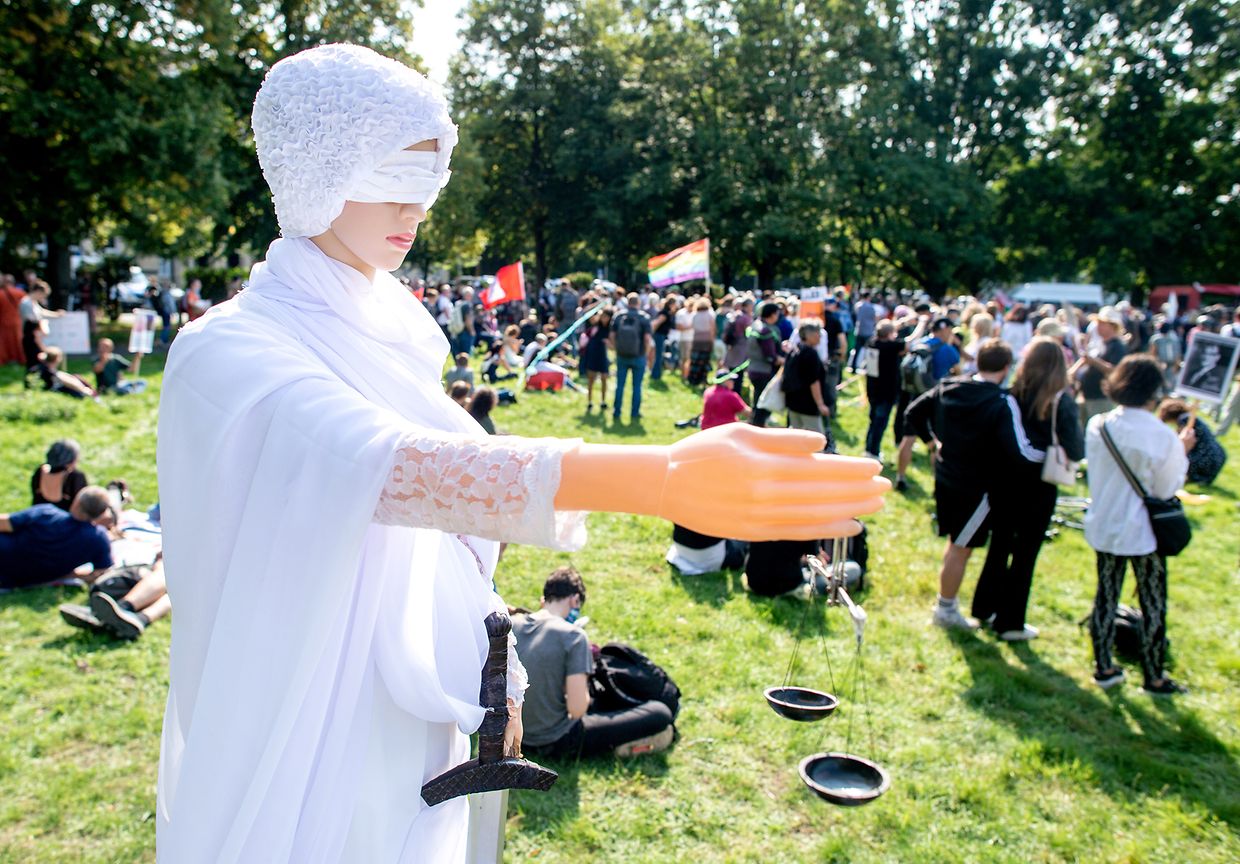 Eine weiße gekleidete Figur, die Justitia, die Göttin der Gerechtigkeit, darstellen soll, steht bei einer Demonstration gegen die Corona-Maßnahmen auf dem Waterlooplatz in Hannover.