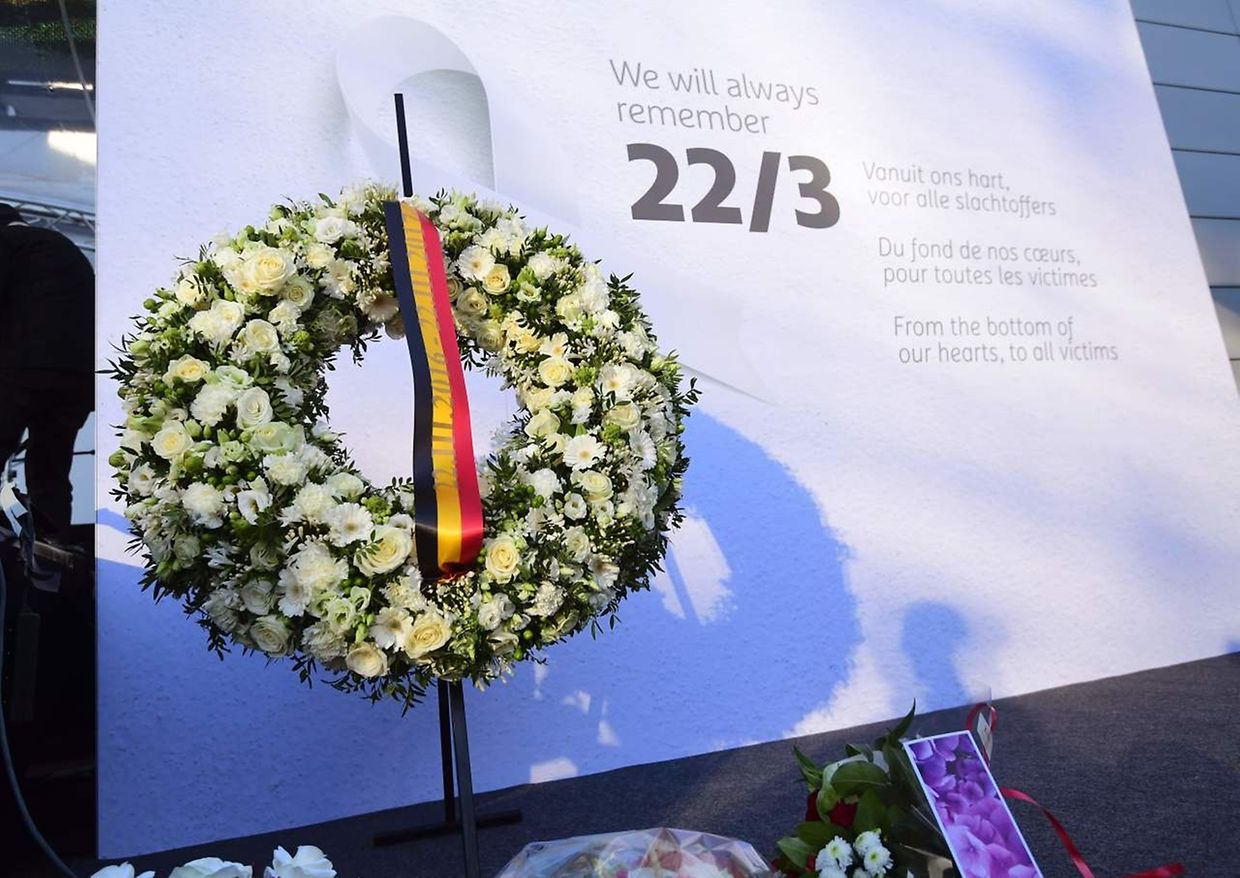 Sur un mur de l'aéroport de Zaventem, une affiche commémorative et une couronne de fleurs pour marquer le premier anniversaire de la double attaque terroriste à Bruxelles.