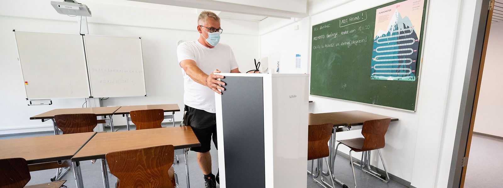 Ein Techniker schiebt einen Luftfilter in einen Klassenraum einer Gesamtschule in Deutschland.
