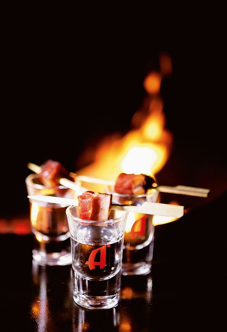 Der "Gin on Fire" bekommt einen gegrillten Baconwürfel am Bambusspieß on top. Er wird zuerst gegessen, der erwärmte Gin hinterhergetrunken.  