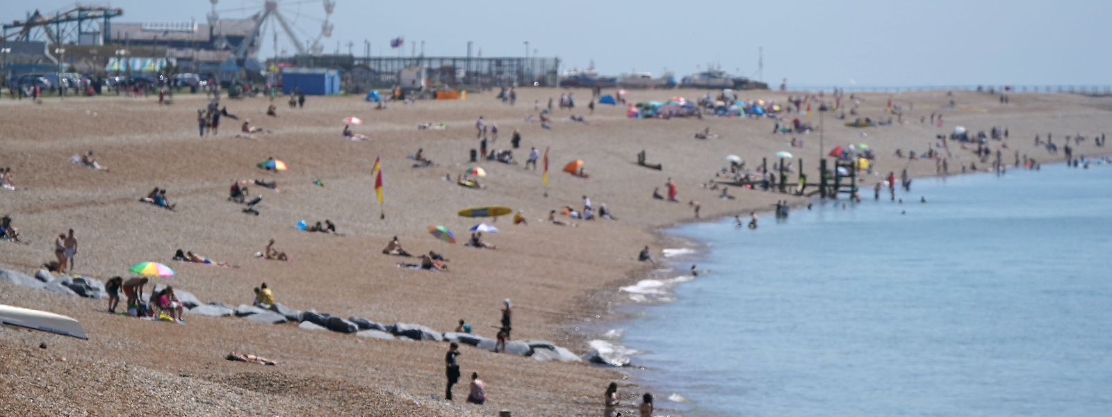 Einige Menschen genießen am Strand von Hastings die Sonne und das warme Wetter. Der "Tag der Freitheit" könnte um vier Wochen nach hinten verlegt werden.