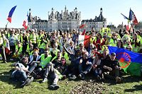 Protestors wearing a "Yellow Vest" (Gilet Jaune) sit and wave French flags in front of Chambord Castle's (Chateau de Chambord) on February 23, 2019 as he came to show his support to "Yellow Vests" (Gilets Jaunes) during a picnic as part of an anti-government demonstration. - 'Yellow vest' protesters take to the streets for 15th consecutive Saturday. (Photo by JEAN-FRANCOIS MONIER / AFP)