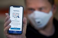 A man holds a smartphone showing a tracking and tracing app launched by the National Institute of Public Health to try to halt a return of the new coronavirus, on April 17, 2020 in Oslo. - Norway, one of the first European countries to begin lifting confinement measures, is launching a smartphone tracking and tracing app that has been developed to provide health authorities a better picture of the spread of COVID-19 and tell users if they have been in contact with the disease. (Photo by Heiko Junge / NTB Scanpix / AFP) / Norway OUT