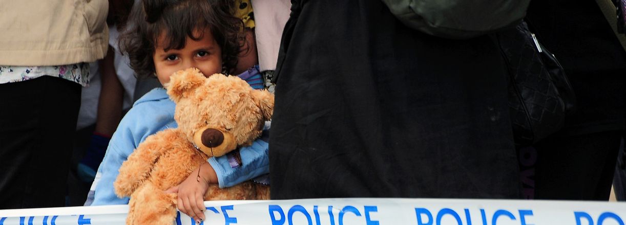 Migrant girl with a teddy bear waits with other migrants for their transport at the police collection point close to the Hungarian-Serbian border near Roszke village on September 6, 2015. Europe is deeply divided over how to handle the continent's biggest refugee crisis since the end of World War II. AFP PHOTO / CSABA SEGESVARI