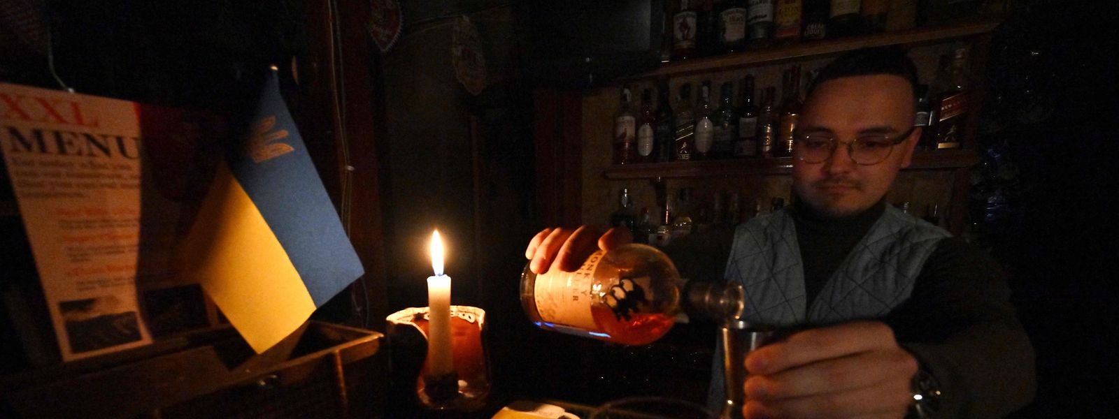 Während eines Stromausfalls schenkt ein Barkeeper im Zentrum der ukrainischen Hauptstadt Kiew bei Kerzenlicht einen Drink ein.