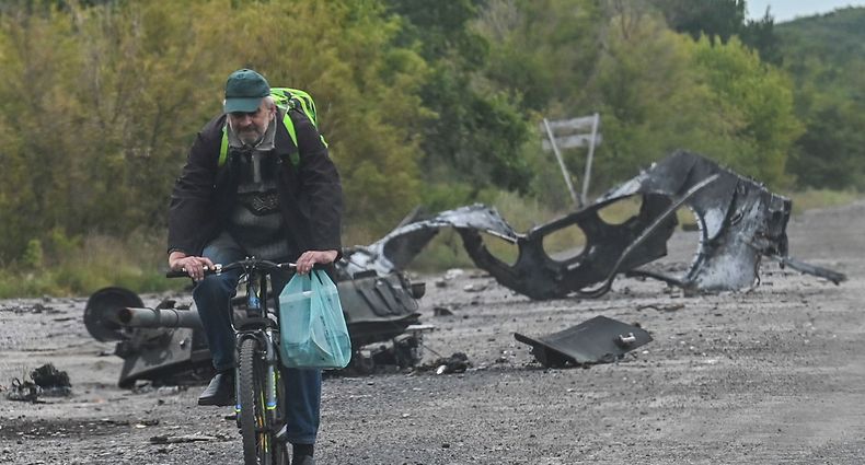 A man rides a bicycle past parts of a destroyed armored vehicle on a road in Balakliya, Kharkiv region, on September 10 , 2022, amid the Russian invasion of Ukraine. - Ukrainian forces said on September 10, 2022 they had entered the town of Kupiansk in eastern Ukraine, dislodging Russian troops from a key logistics hub in a lightning counter-offensive that has seen swathes of territory recaptured. (Photo by Juan BARRETO / AFP)