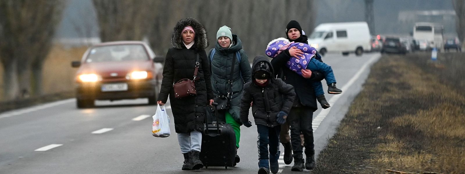 Refugiados da Ucrânia caminham numa estrada após atravessarem o posto de controlo da fronteira com a Moldávia perto da cidade de Palanca.