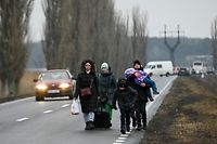 Refugiados da Ucrânia caminham numa estrada após atravessarem o posto de controlo da fronteira com a Moldávia perto da cidade de Palanca.