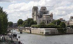 (FILES) In this file photo taken on June 15, 2019 people gather along Pont de l'Archeveche bridge over the River Seine that leeds to Ile de la Cite and the Notre-Dame de Paris cathedral, in Paris. - Pressure rises on French authorities after an NGO files a lawsuit accusing them of failing to quickly contain the risks of lead poisoning after the fire that ravaged Notre-Dame cathedral in Paris last April. (Photo by Zakaria ABDELKAFI / AFP)