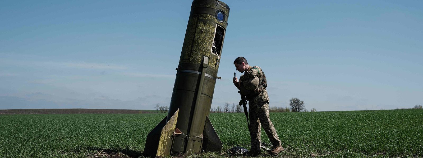 Um soldado ucraniano olha para o destroço de um míssil balístico russo que caiu num campo em Bohodarove, no leste da Ucrânia.