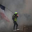 A man holding a French flag and a yellow vest walks in tear gas during a rally against the pension overhauls, in Paris, on December 5, 2019 as part of a nationwide strike. - Trains cancelled, schools closed: France scrambled to make contingency plans on for a huge strike against pension overhauls that poses one of the biggest challenges yet to French President's sweeping reform drive. (Photo by Zakaria ABDELKAFI / AFP)