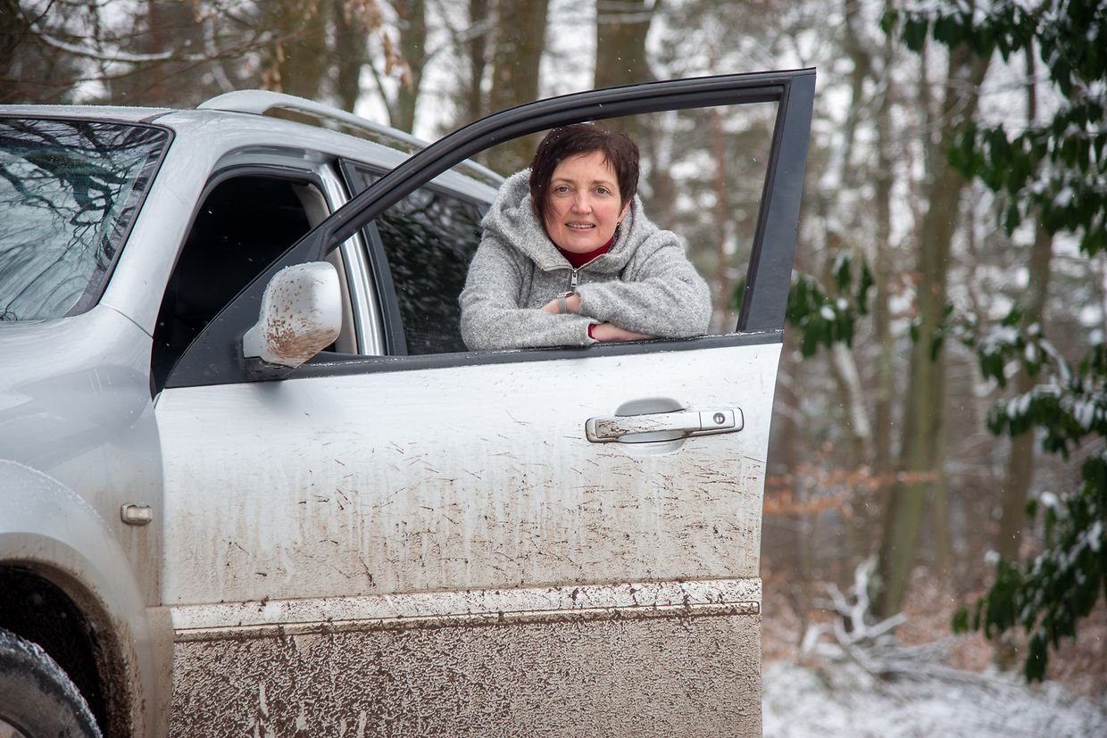 Sonja Reuter-Höling lehnt auf einem Waldweg an einem Allrad-Fahrzeug. Der Landkreis Trier-Saarburg hat das Geländeauto nach einem Erdrutsch, der den Ortsteil Hochmark von anderen Orten abgeschnitten hat, zur Verfügung gestellt.