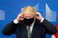 Britain's Prime Minister Boris Johnson (L) adjusts his facemask at a press meet in the Berlaymont building at the EU headquarters in Brussels on December 9, 2020, prior to a post-Brexit talks' working dinner with European Commission President Ursula von der Leyen. - Prime Minister Boris Johnson met EU chief Ursula von der Leyen on Wednesday for a working dinner that could save -- or kill off -- hopes for a post-Brexit trade deal. (Photo by Aaron Chown / POOL / AFP)