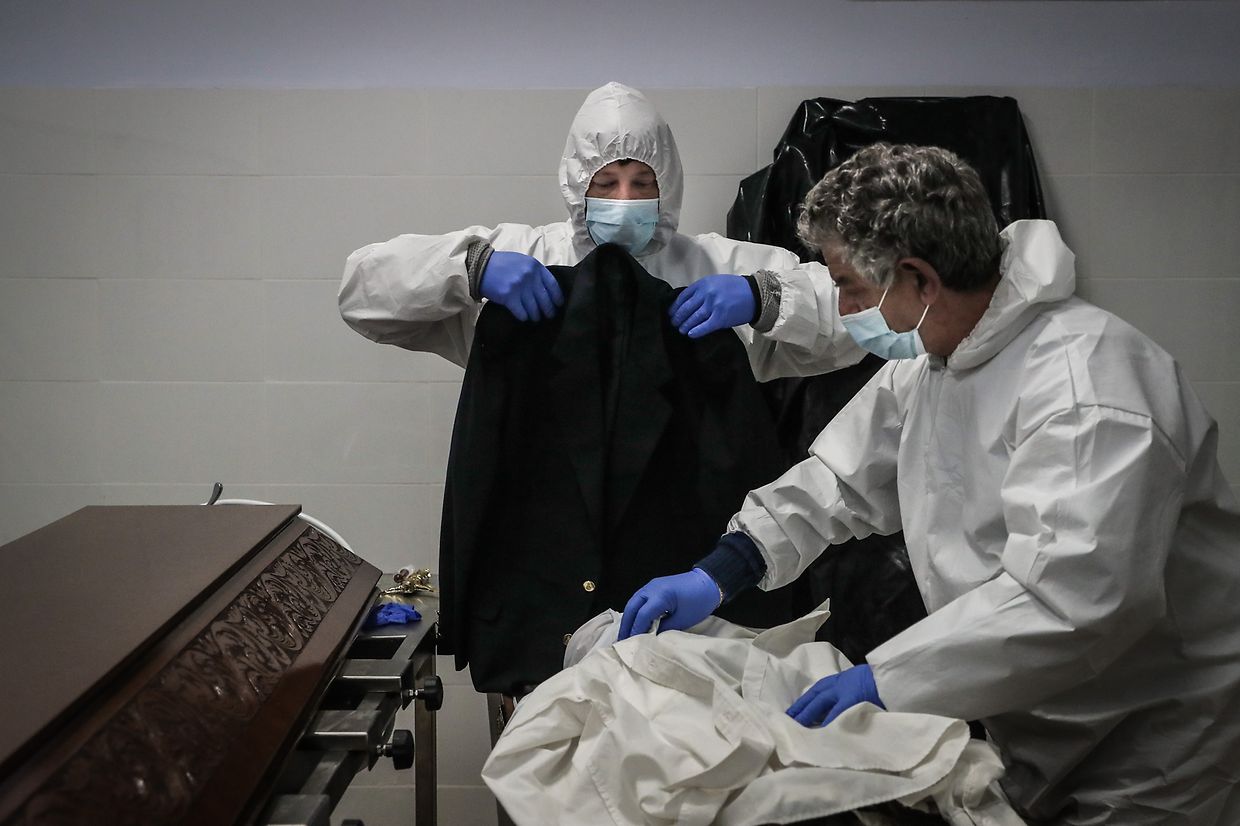 Funcionários de uma agência funerária seguram as roupas de um homem que faleceu com suspeitas de estar infetado com covid-19, na Amadora, a 30 de janeiro de 2021.