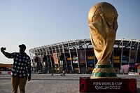 A man takes a picture in front of a replica of the World Cup trophy outside the Stadium 974 in Doha on November 15, 2022, ahead of the Qatar 2022 World Cup football tournament. (Photo by Kirill KUDRYAVTSEV / AFP)
