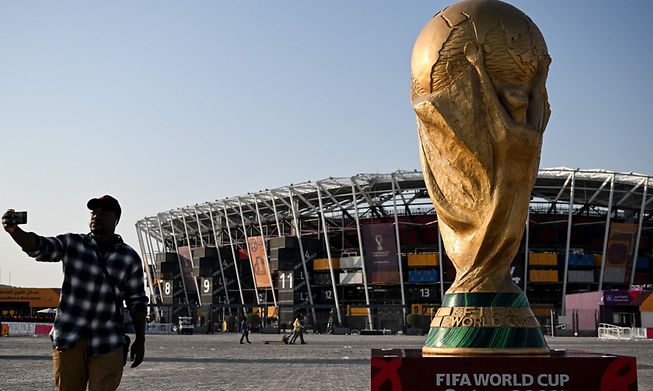 A man takes a picture in front of a replica of the World Cup trophy outside the Stadium 974 in Doha, Qatar, on November 15