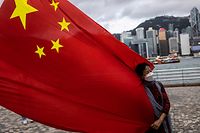 A woman holds the Chinese flag to celebrate the 25th anniversary of the city's handover from Britain to China, in Hong Kong on July 1, 2022. (Photo by ISAAC LAWRENCE / AFP)