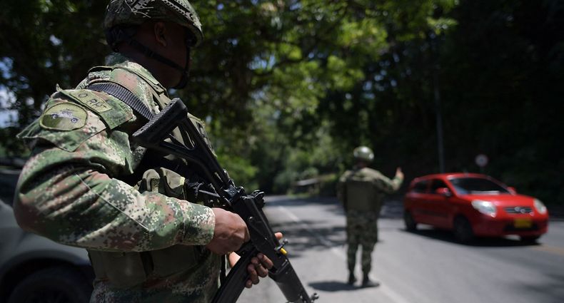Colombian soldiers guard a road during a mining strike in Taraza Municipality, Cauca department, Colombia on March 21, 2023. - Colombian President Gustavo Petro ordered, on March 19, 2023, the resumption of offensive actions against the Clan del Golfo, Colombia's largest drug gang, for attacks on civilians and the security forces, which led him to suspend the ceasefire. The government said the group had been supporting attacks by illegal gold miners since March 2 in the country's northwestern Antioquia department. Workers in illegal mines have been protesting the government's destruction of the heavy machinery they use to dredge up soil to find gold. (Photo by Raul ARBOLEDA / AFP)