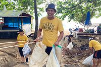 PRODUKTION - 19.10.2022, Indonesien, Sanur: Wayan Maja, der die Aktionen der «Trash Heroes» in Teilen von Bali koordiniert, verteilt wiederverwendbare Müllsäcke zum Beginn einer Sammelaktion. Eine kleine Gruppe von Umweltschützern zieht am frühen Morgen über den Strand von Sanur. Sie tragen gelbe T-Shirts mit der Aufschrift «Trash Hero» - Müllheld . (zu dpa: «Plastik im Paradies: Trauminsel Bali zwischen Magie und Müllbergen») Foto: Carola Frentzen/dpa +++ dpa-Bildfunk +++