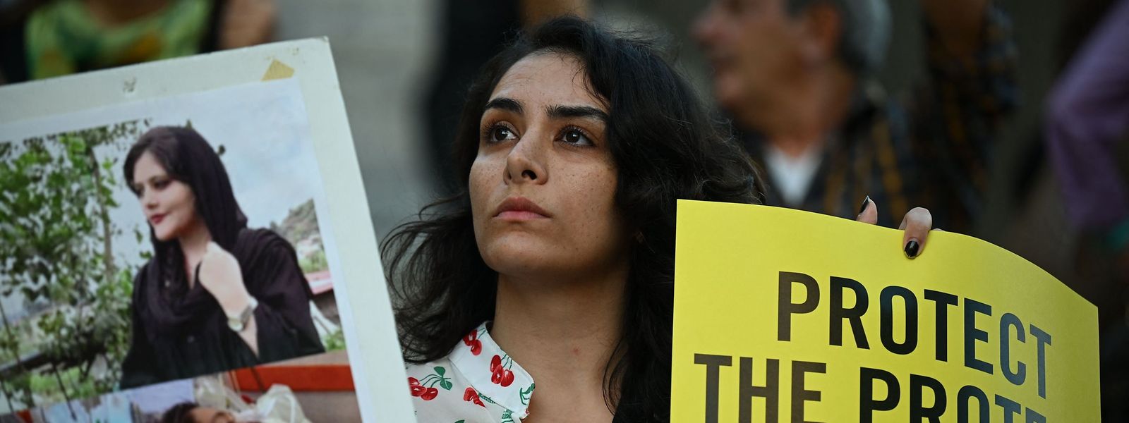 Um manifestante mostra fotografias da jovem curda iraniana Mahsa Amini durante um protesto na Piazza del Campidoglio, em Roma, a 5 de outubro