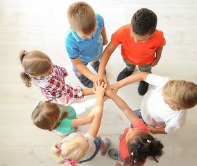 Little children putting their hands together indoors, top view. Unity concept