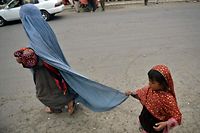 A burqa-clad woman walks with her children along a street in Kabul on August 31, 2021. (Photo by Hoshang Hashimi / AFP)