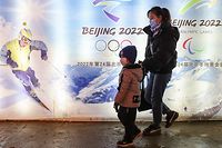 BEIJING, CHINA - FEBRUARY 26:  People wear protective masks as they walk front the logos of the 2022 Beijing Winter Olympics at Yanqing Ice Festival on February 26, 2021 in Beijing, China. The Festival comes at the final day of the Chinese Lunar New Year celebrations. (Photo by Lintao Zhang/Getty Images)