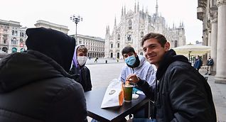 People sit at a cafe's terrace close to Duomo square in central Milan on Monday. Bars, restaurants, cinemas and concert halls partially reopened across Italy on Monday as parliament debated the government's €220-billion, EU-funded recovery plan. 
