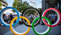 TOPSHOT - People gather near the Olympic Rings to take pictures of the Blue Impulse aerobatic demonstration team of Japan Air Self-Defence Force flying over the Olympic Stadium, the main venue for the Tokyo 2020 Olympic and Paralympic Games, during a rehearsal in Tokyo on July 21, 2021. (Photo by Philip FONG / AFP)