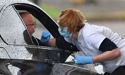 A medical worker tests a key worker for the novel coronavirus COVID-19 at a drive-in testing facility at the Chessington World of Adventures Resort in Greater London on April 28, 2020. - Britain's health ministry on April 27 said the total toll of those having died after testing positive for COVID-19 in hospital had risen to 21,092. (Photo by Ben STANSALL / AFP)