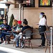 A waitress takes customers' orders in the outdoor seating area of a restaurant on January 28, 2021 in Los Angeles. - California lifted blanket "stay-at-home" orders across the US state on Jaunary 25, paving the way for activities such as outdoor dining to return even in worst-hit regions as the pandemic's strain on hospitals begins to ease. (Photo by VALERIE MACON / AFP)