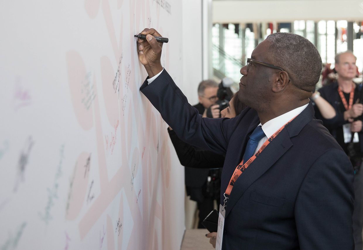 Friedensnobelpreisträger Denis Mukwege verewigt sich auf der Teilnehmerwand.