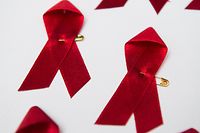 ARCHIV - 01.12.2014, Berlin: Viele rote Schleifen, das weltweit anerkannte Symbol für die Solidarität mit HIV-Infizierten, liegen am Welt-Aids-Tag auf einem Tisch. Am 01.12.2021 ist der Welt-Aids-Tag.    (zu dpa «Zahl der HIV-Infektion 2020 gesunken - Nun wieder steigende Tendenz») Foto: Lukas Schulze/dpa +++ dpa-Bildfunk +++