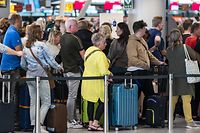 Niederlande, Schiphol: Reisende stehen in der Abflughalle des Flughafens Schiphol Schlange.