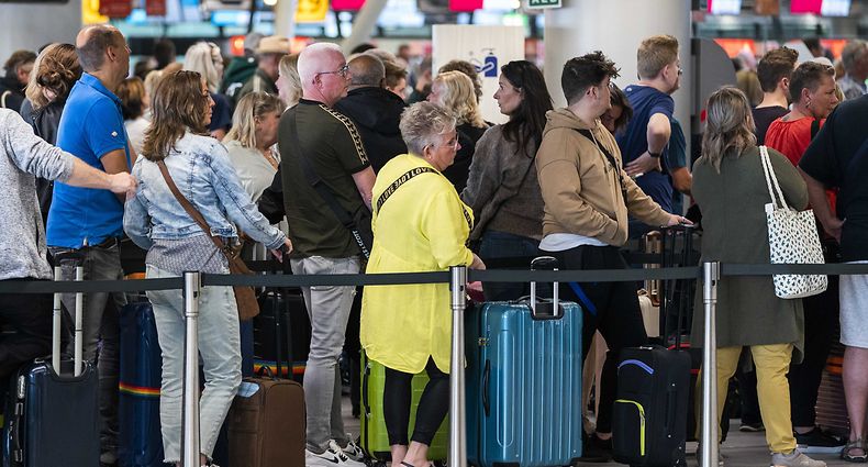Niederlande, Schiphol: Reisende stehen in der Abflughalle des Flughafens Schiphol Schlange.