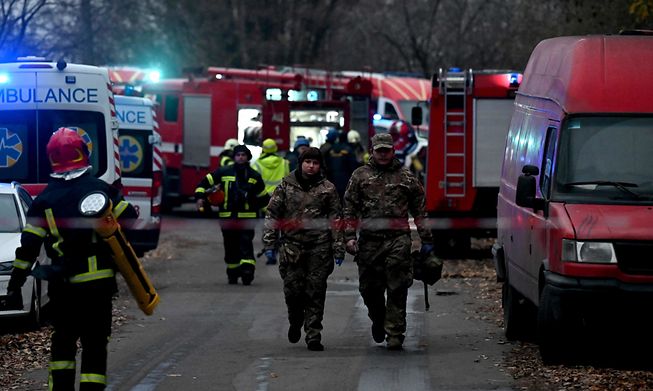 Ukrainian firefighters and emergency personnel at the scene where a Russian missile fragment fell near a residential building in Kyiv on Tuesday