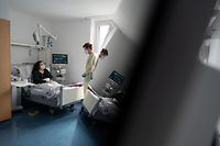 dpatopbilder - 22.02.2022, Baden-Württemberg, Stuttgart: Gregor Paul (r), Oberarzt, unterhält sich in einem Patientenzimmer einer Covid-19-Station im Klinikum Stuttgart mit Patientin Ioanna Maag-Nikolopoulou. Es ist ein neues Phänomen: Die Corona-Pandemie verlagert sich stärker auf die Normalstationen der Krankenhäuser. Denn bei vielen Patienten wird das Virus zur Nebendiagnose. (zu dpa "Wenn Corona das kleinere Übel ist") Foto: Marijan Murat/dpa +++ dpa-Bildfunk +++